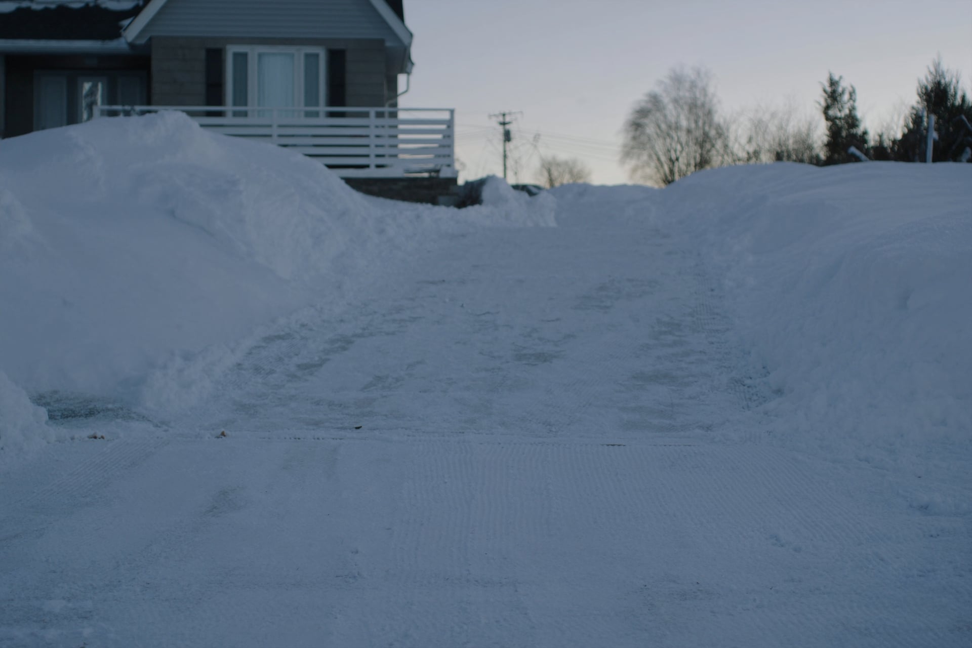 Entrée résidentielle fraîchement déneigée au petit matin avec tas de neige sur les côtés